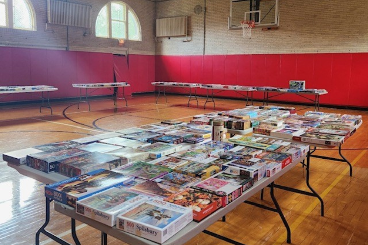 Photograph of tables covered with puzzle boxes in a gymnasium.